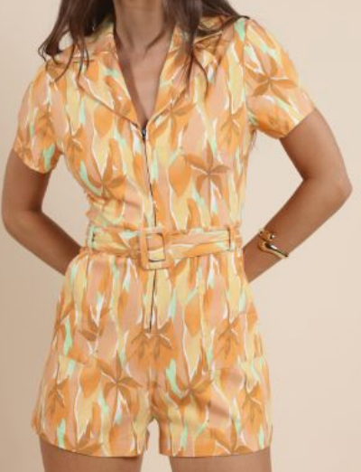 Woman wearing a floral patterned romper on a beige background. Amanda Palm Printed Romper, a staple for curated boutique fashion and chic affordable style available at your Womens Boutique West Palm Beach, FL.