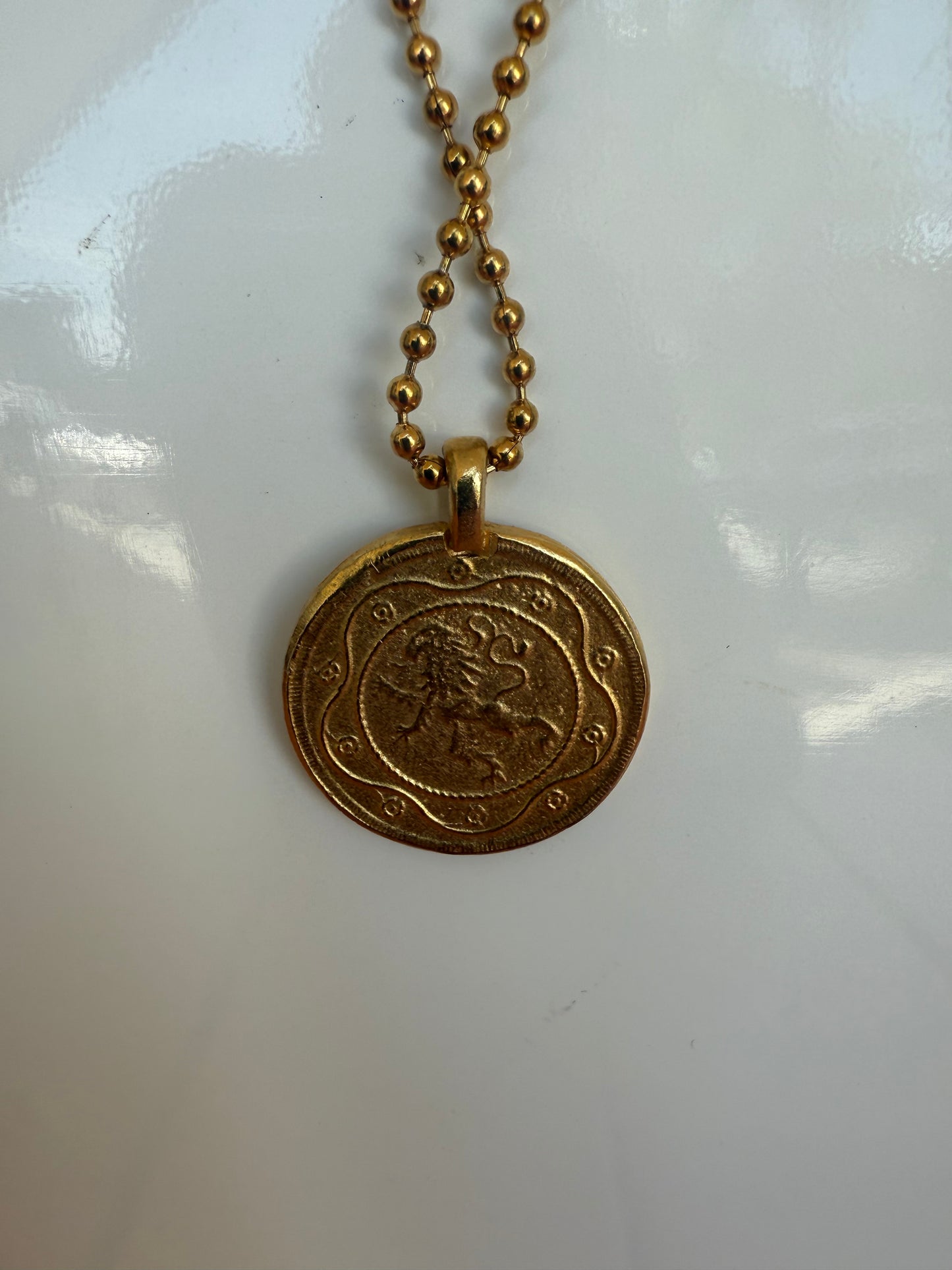 Gold necklace with a round pendant on a white background