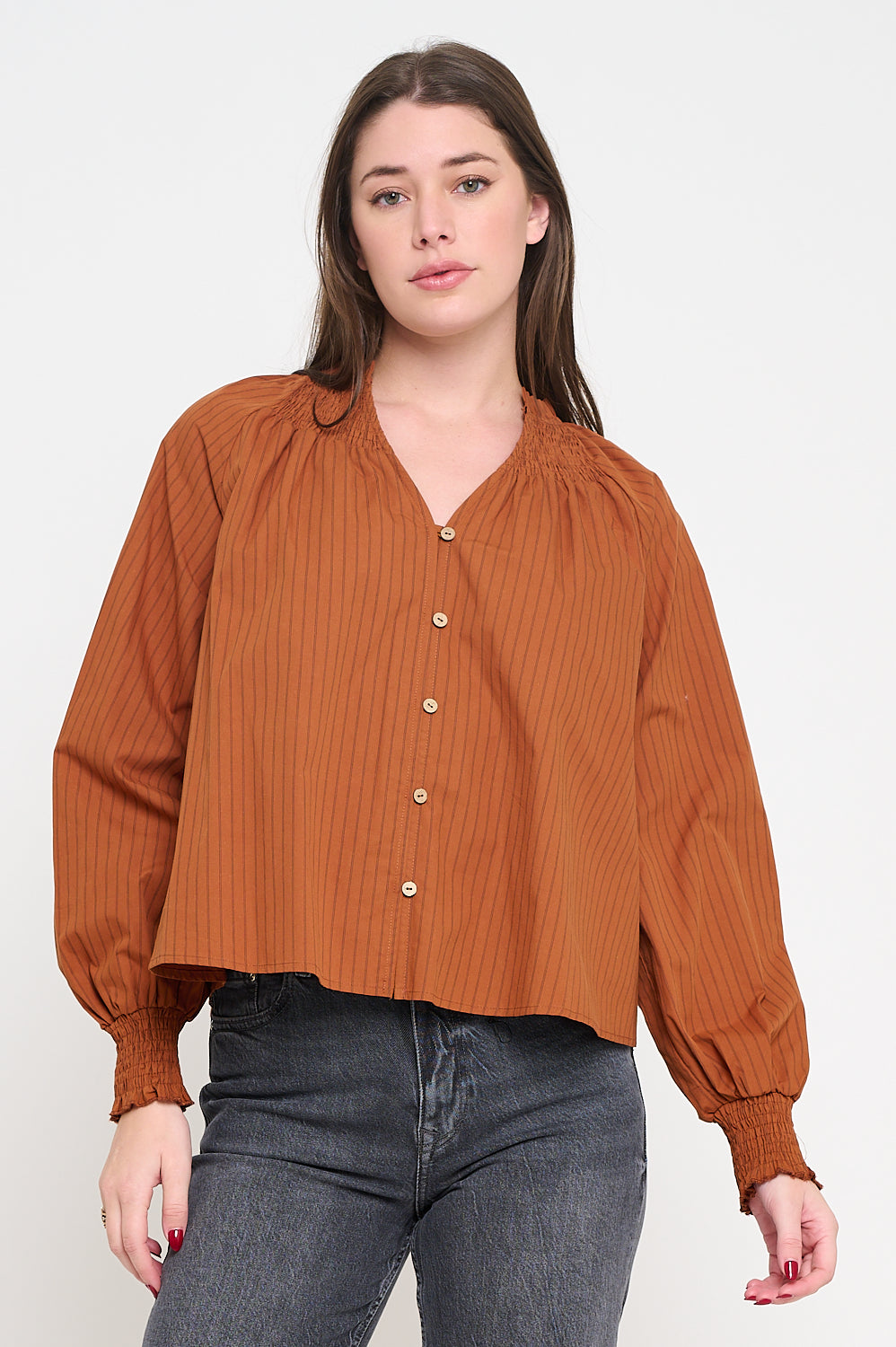 Woman wearing a brown blouse with balloon sleeves on a white background,Kirstie Long Sleeve Terracotta Brown Blouse, a staple for curated boutique fashion and chic affordable style available at your Womens Boutique West Palm Beach, FL.