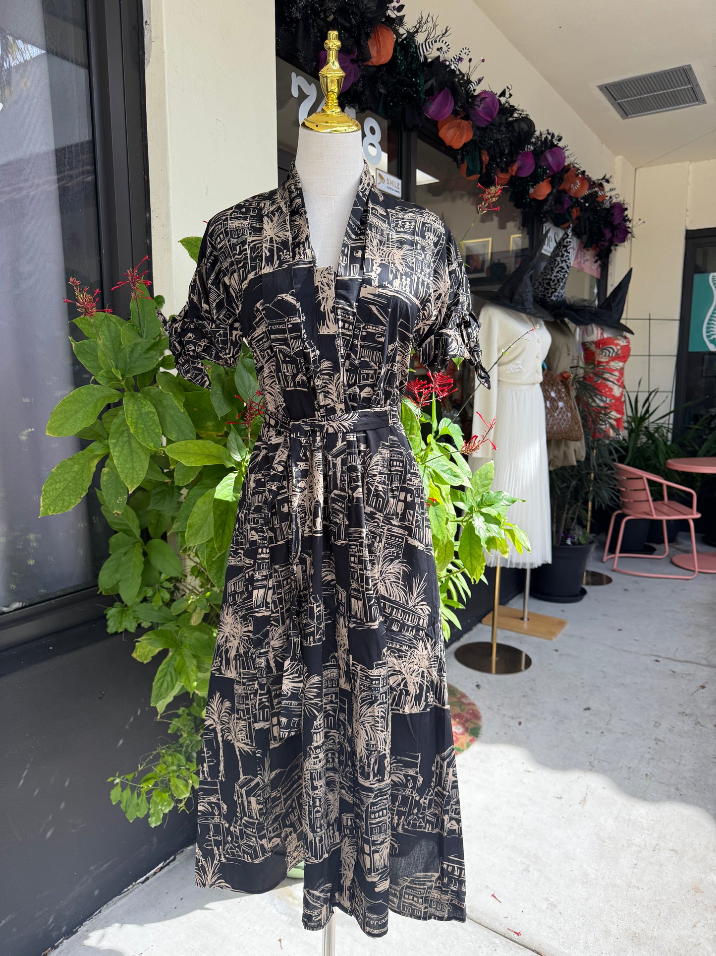 Mannequin wearing a black and white patterned dress with greenery in an indoor setting, Blue tracksuit on a mannequin with a decorative background. a staple for curated boutique fashion and chic affordable style available at your Womens Boutique West Palm Beach, FL.