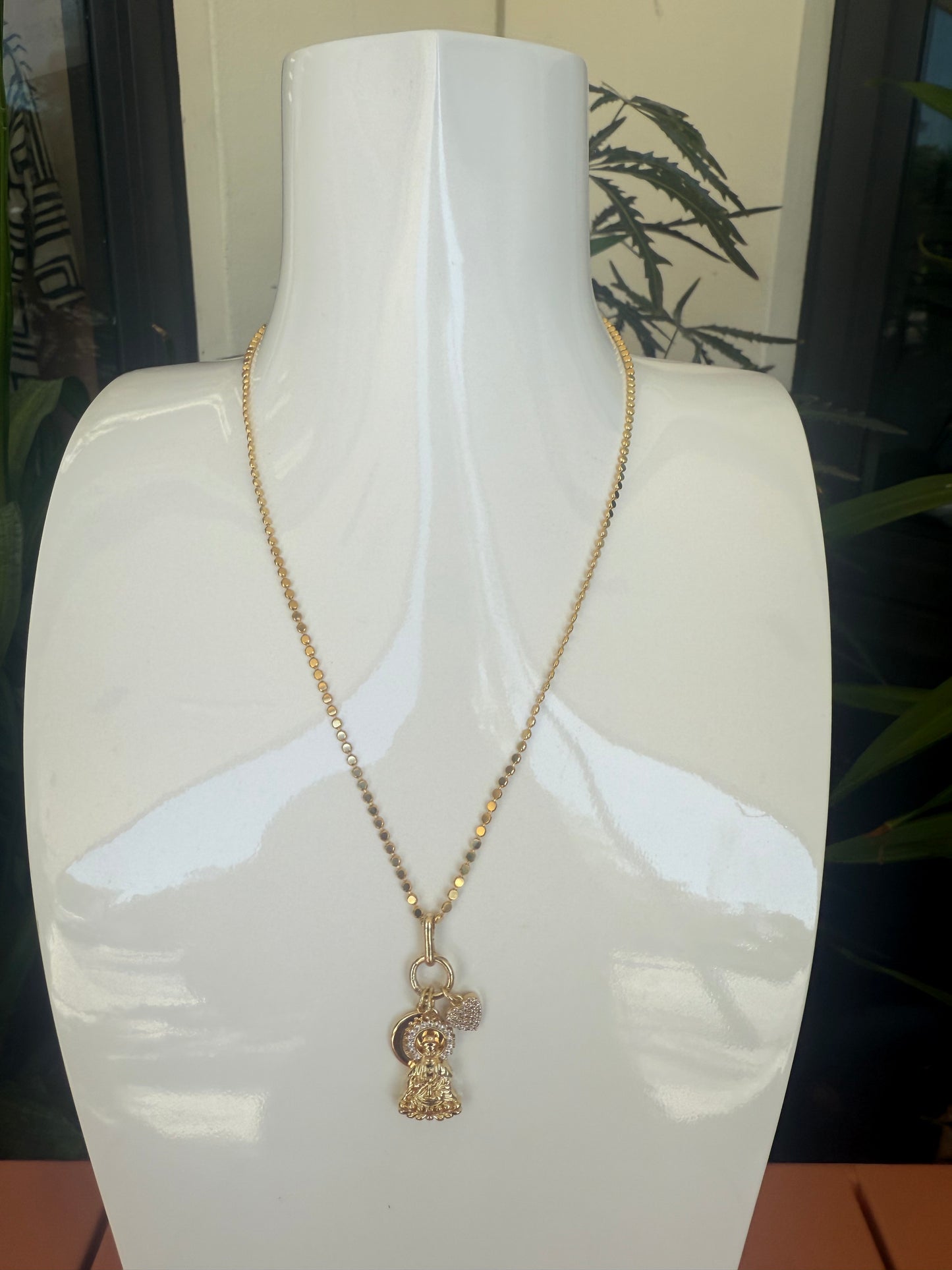 Gold necklace with a heart-shaped pendant on a white background, Short Necklace with Buddha, Heart & Moon CZ charm, a staple for curated boutique fashion and chic affordable style available at your Womens Boutique West Palm Beach, FL.