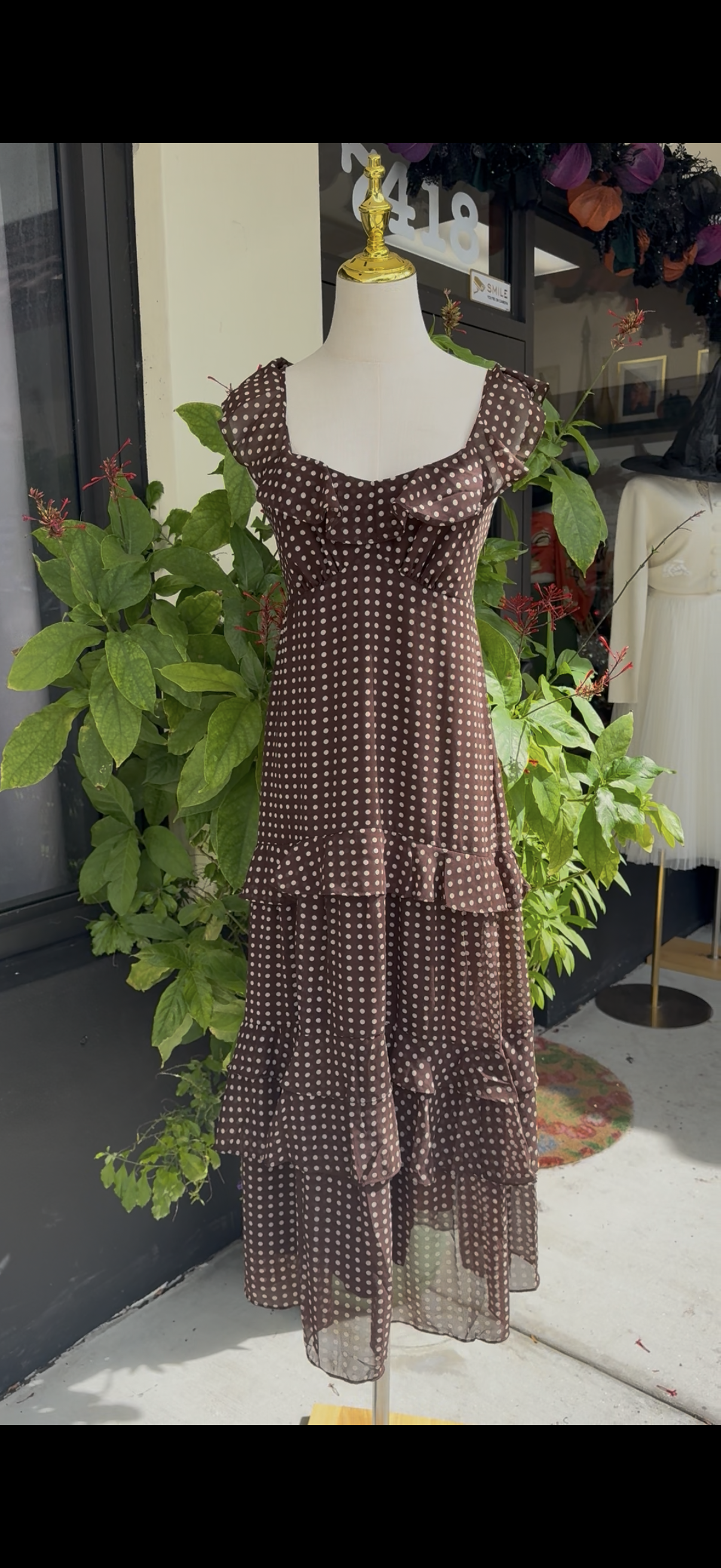 Mannequin wearing a brown patterned dress in a store setting with plants and furniture.Blue tracksuit on a mannequin with a decorative background. a staple for curated boutique fashion and chic affordable style available at your Womens Boutique West Palm Beach, FL.