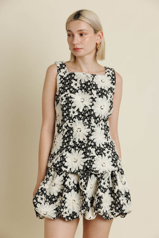 Woman wearing a black and white floral dress against a beige background.  a staple for curated boutique fashion and chic affordable style available at your Womens Boutique West Palm Beach, FL.