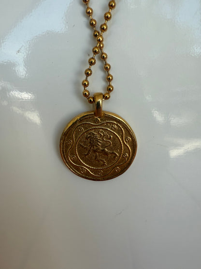 Gold necklace with a round pendant on a white background