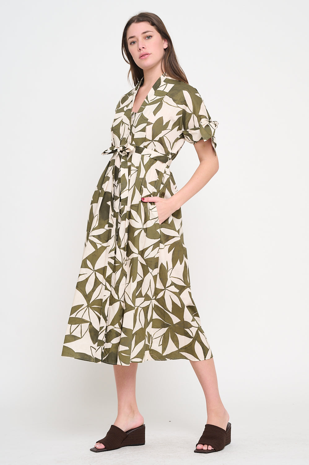 Woman wearing a green leaf-patterned dress on a white background, Bonnie Canopy Shirt Dress, a staple for curated boutique fashion and chic affordable style available at your Womens Boutique West Palm Beach, FL.