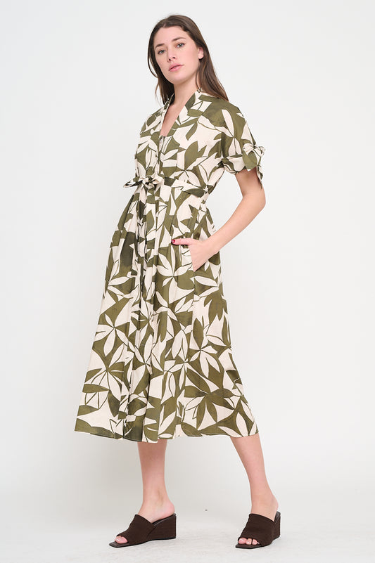 Woman wearing a green leaf-patterned dress on a white background, Bonnie Canopy Shirt Dress, a staple for curated boutique fashion and chic affordable style available at your Womens Boutique West Palm Beach, FL.