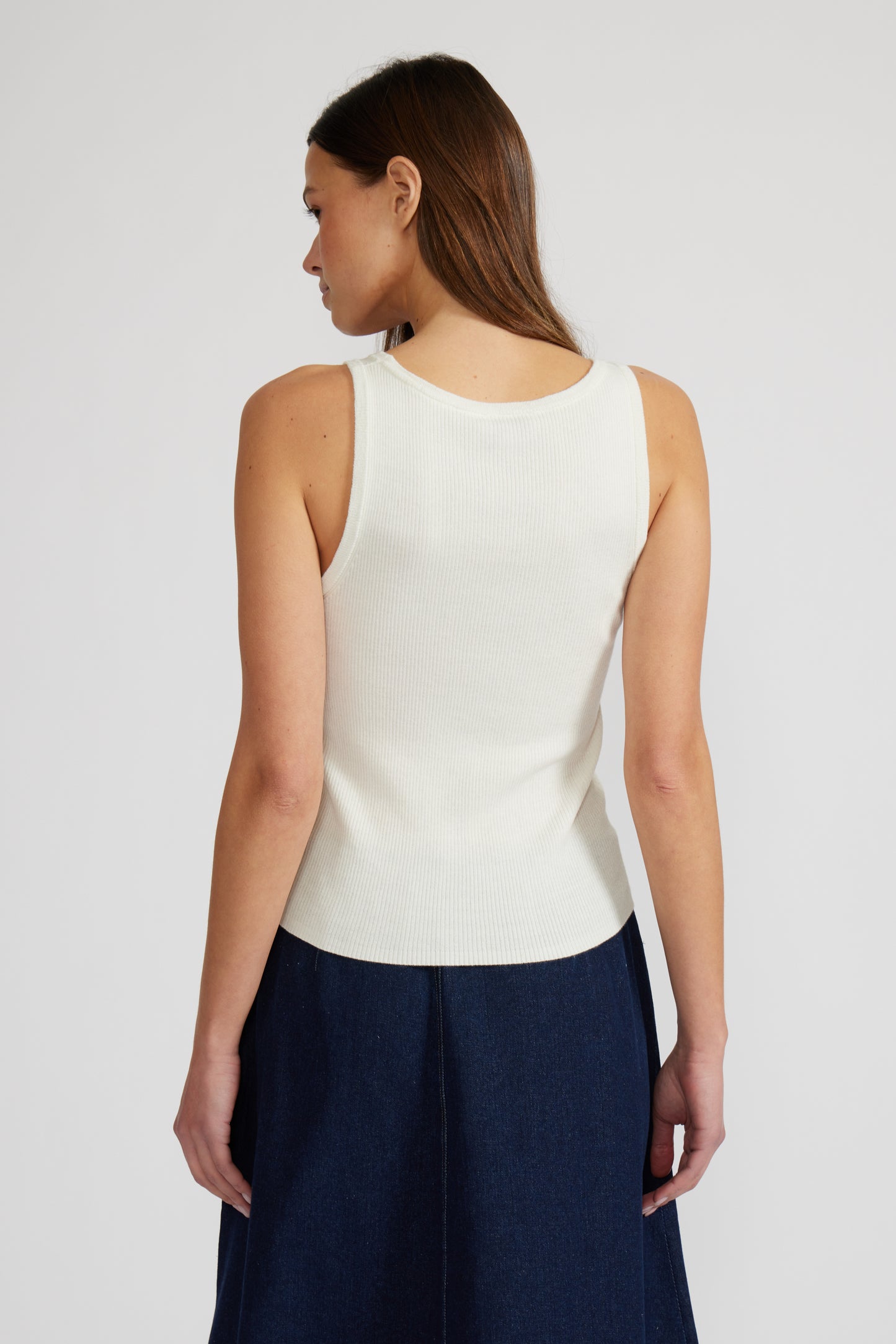 Woman wearing a white sleeveless top and navy pants on a plain background. Doreen Rhinestone Tank,  a staple for curated boutique fashion and chic affordable style available at your Womens Boutique West Palm Beach, FL.