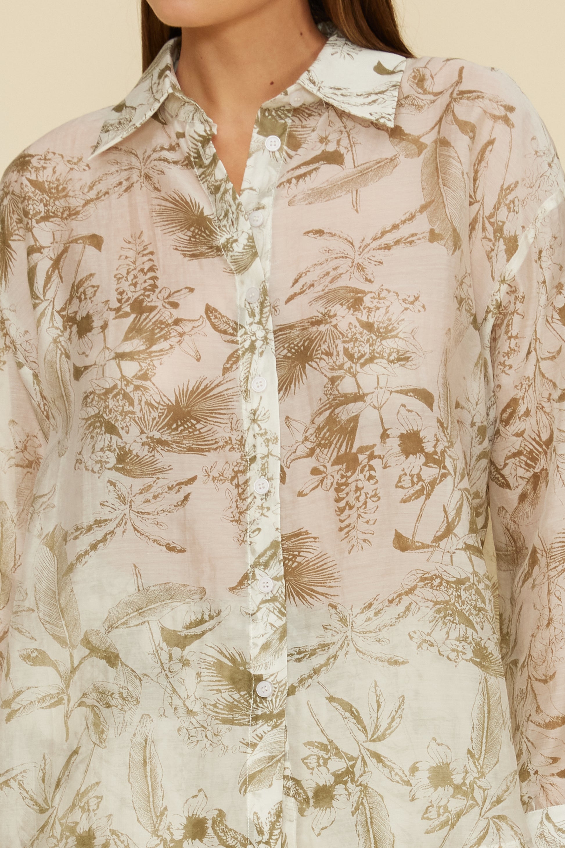 Floral patterned shirt worn by a person on a beige background.  Printed button down shirt. Esme Printed Button Down Shirt, a staple for curated boutique fashion and chic affordable style available at your Womens Boutique West Palm Beach, FL.