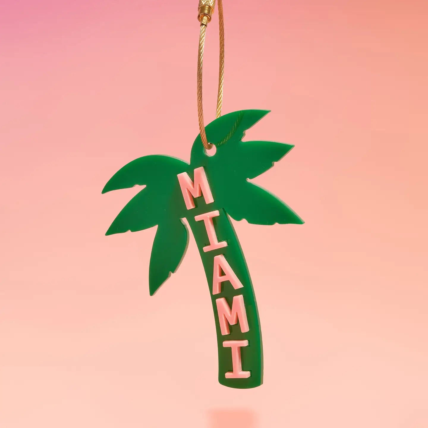 Green palm tree-shaped ornament with 'MIAMI' text on a pink background