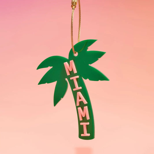 Green palm tree-shaped ornament with 'MIAMI' text on a pink background