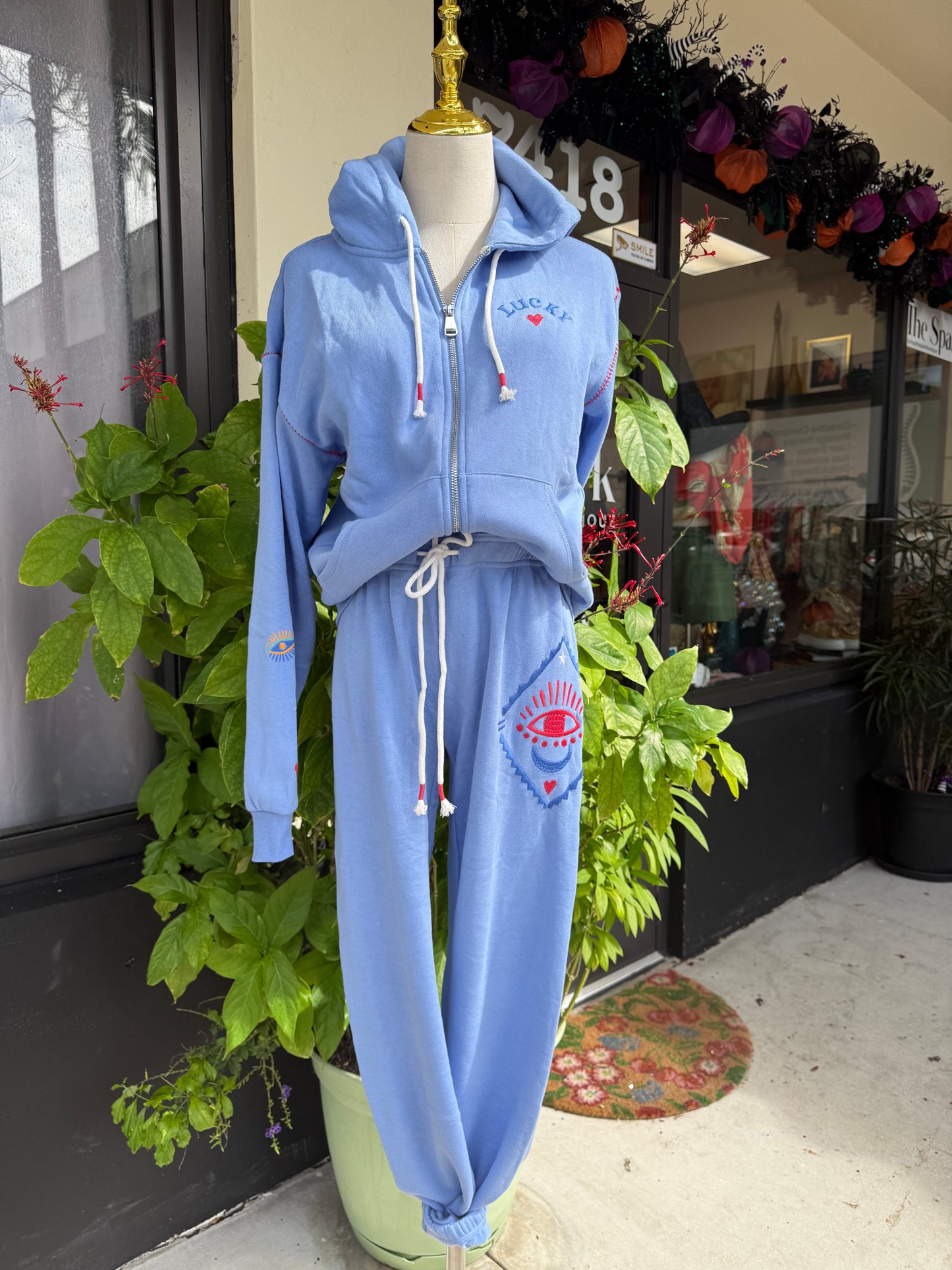 Blue tracksuit on a mannequin with a decorative background. a staple for curated boutique fashion and chic affordable style available at your Womens Boutique West Palm Beach, FL.
