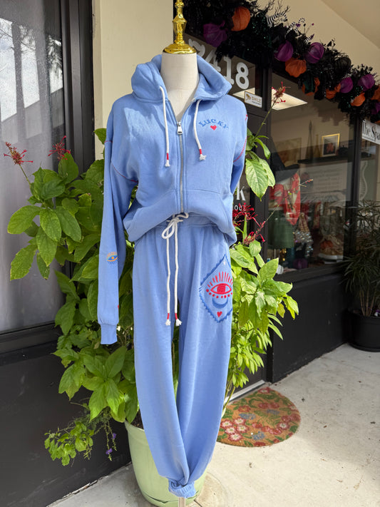 Blue tracksuit on a mannequin with a decorative background. a staple for curated boutique fashion and chic affordable style available at your Womens Boutique West Palm Beach, FL.
