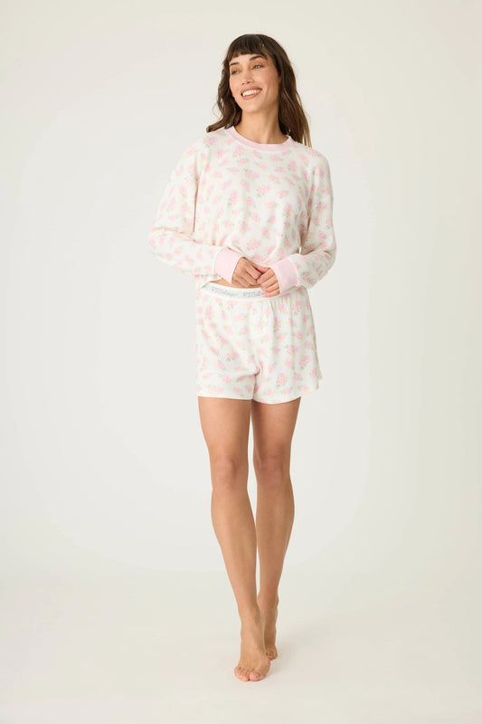 Woman wearing a white long-sleeve top and shorts with pink floral pattern on a white background, Rosie Printed PJ set BF Boxer Shorts, a staple for curated boutique fashion and chic affordable style available at your Womens Boutique West Palm Beach, FL.
