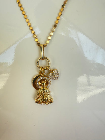 Gold necklace with a heart-shaped pendant on a white background, Short Necklace with Buddha, Heart & Moon CZ charm, a staple for curated boutique fashion and chic affordable style available at your Womens Boutique West Palm Beach, FL.
