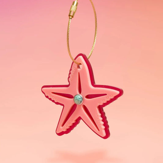 Pink starfish ornament with a gold chain on a pink background