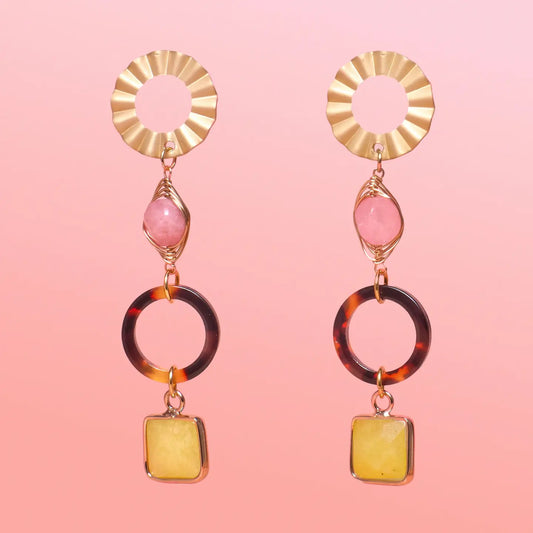 Pair of gold, tortoiseshell, and yellow earrings on a pink background
