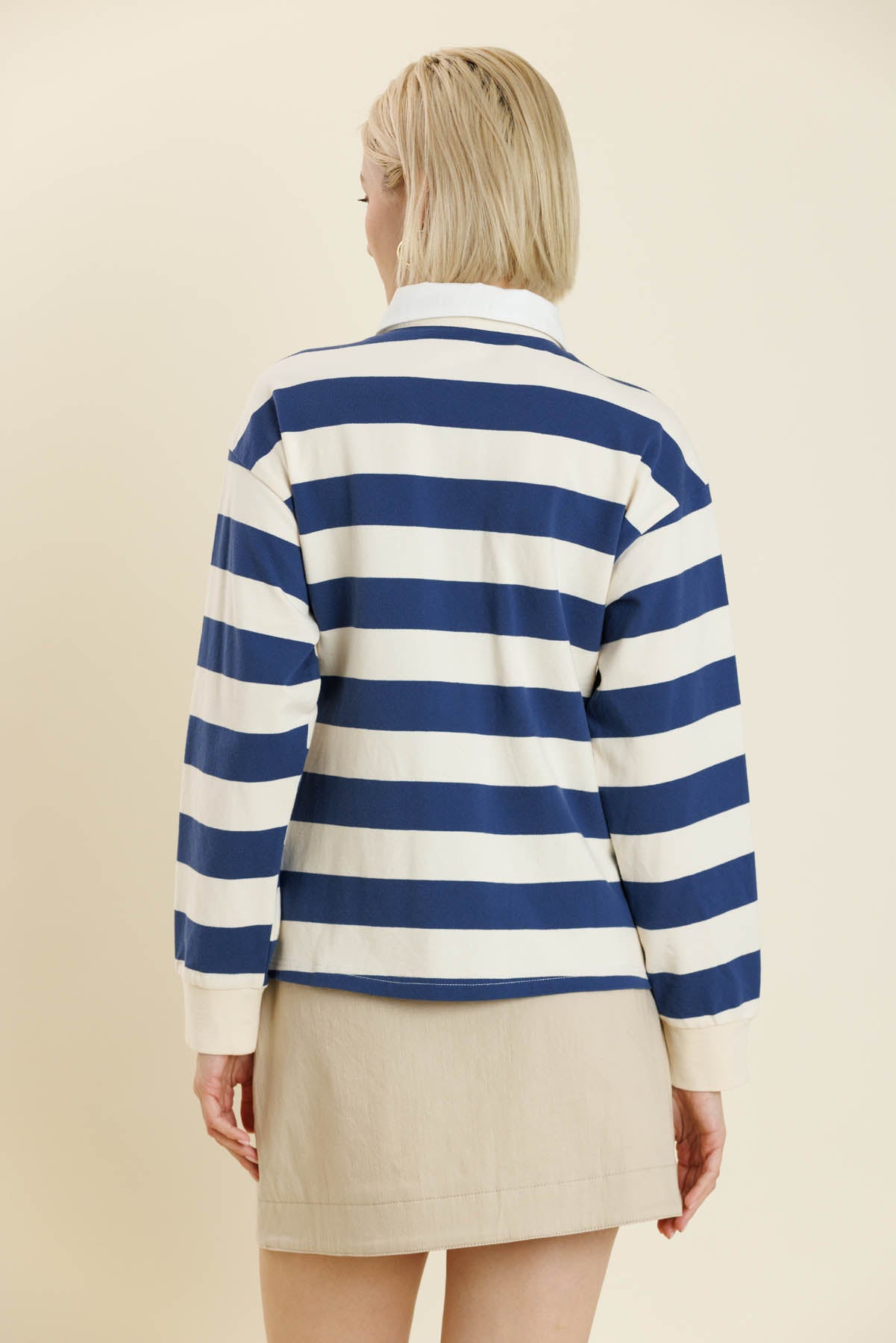 Person wearing a blue and white striped sweater with a beige skirt on a plain background. Yara Striped L/S Shirt, a staple for curated boutique fashion and chic affordable style available at your Womens Boutique West Palm Beach, FL.
